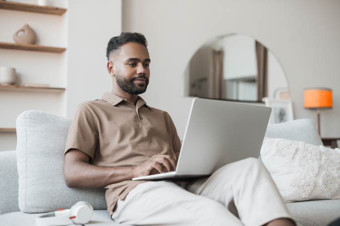 Young man sitting on a couch working on his laptop