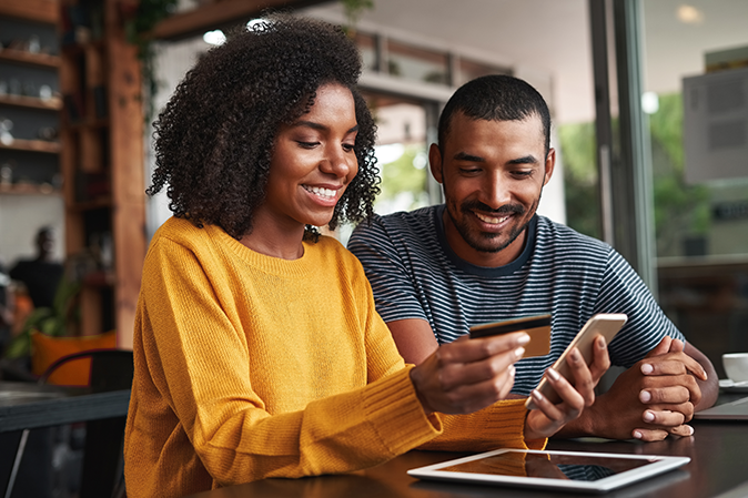 Young woman and man using a credit card to make an online payment